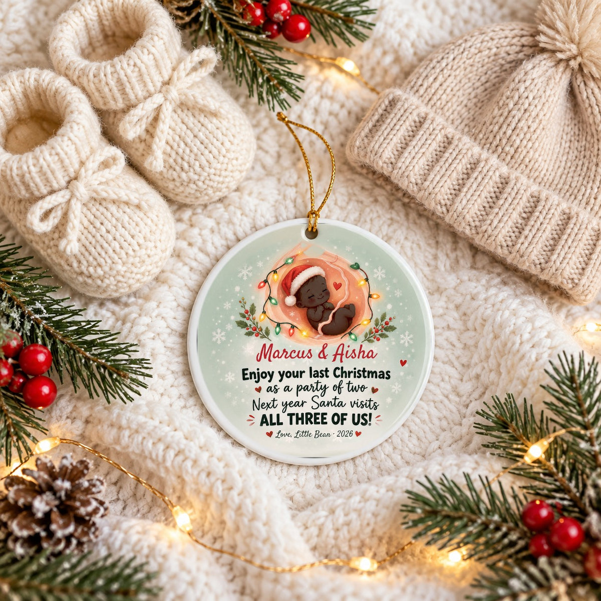 Custom pregnancy Christmas ornament Marcus & Aisha with deep brown baby skin tone, flat lay with baby booties